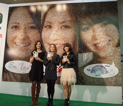 特大コラージュアートの前で「スマイル!!」の浦浜アリサ、亀恭子、村上萌