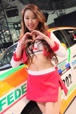 来場者にハートのサインを送る三菱自動車のコンパニオン