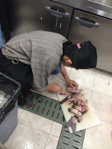 床にまな板を置いて調理する中国人スタッフ