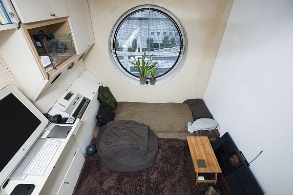 この部屋の住人はDIYで内装を変更し、丸窓に合わせて切った板を壁に貼り付けておしゃれに演出