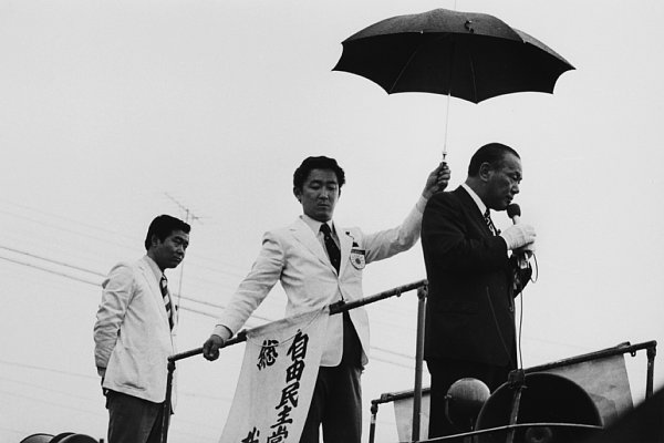 田中角栄氏に傘をさしかける橋本龍太郎氏（1974年）