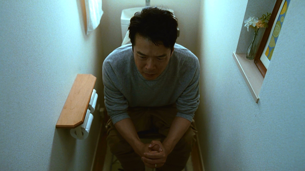 トイレにこもり切なげな表情のタケシ・49歳を演じる田中哲司