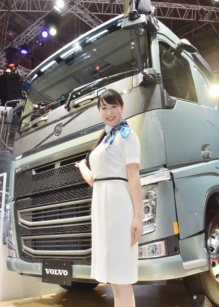 VOLVOの大型トラックの前で微笑む美女コンパニオン