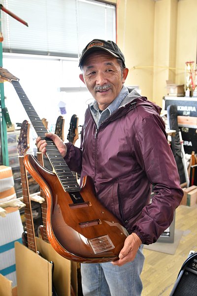 製作途中のベースを手にするSugiギターの創業者・杉本眞氏