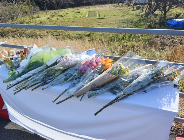 事故現場の献花台を多数の地元住人が訪れている