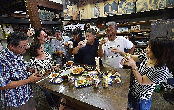 客が持ち寄ったつまみを囲み主人（右から3人目）が一緒に飲むことも