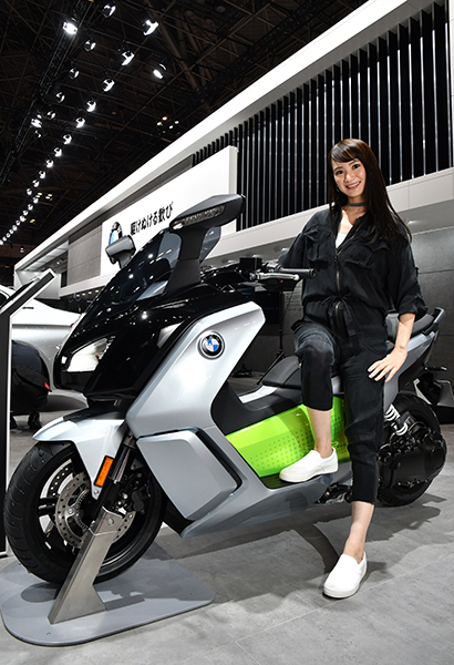 BMWのブースで見つけた新型バイクに腰をかけるデニム美女
