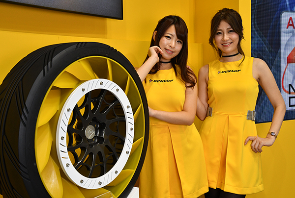 パンクしないダンロップの新型タイヤの前でポースを取る2人