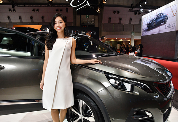 プジョーブースの新型車の前でポーズを取る美女コンパニオン