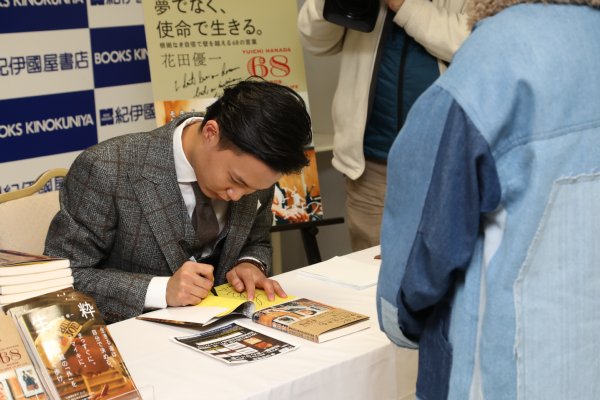 丁寧にサインをする花田優一氏