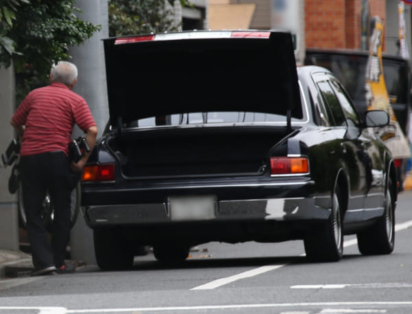 お抱えの運転手が車椅子を自宅に運び入れる