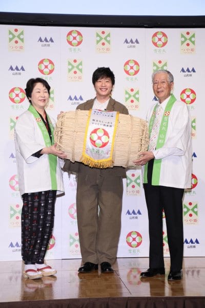 米俵を持つ田中圭と山形県の吉村美栄子知事とJA山形中央会会長の長澤豊氏