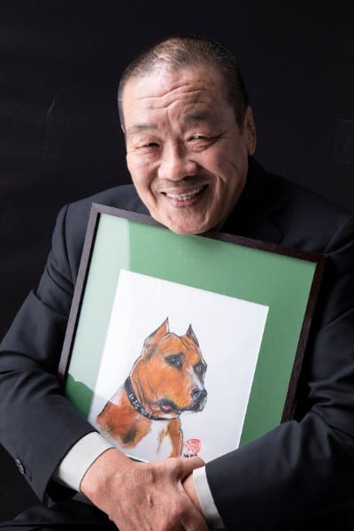 愛犬の絵を手に微笑む藤原喜明