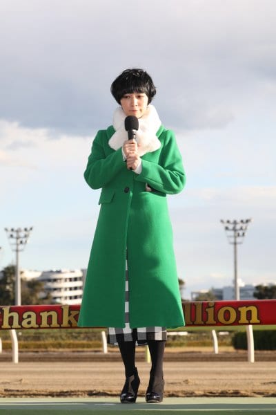 鮮やかな緑のコートを着用する吉谷彩子