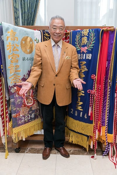 愛馬の優勝レイの前でポーズをとるDr.コパ氏