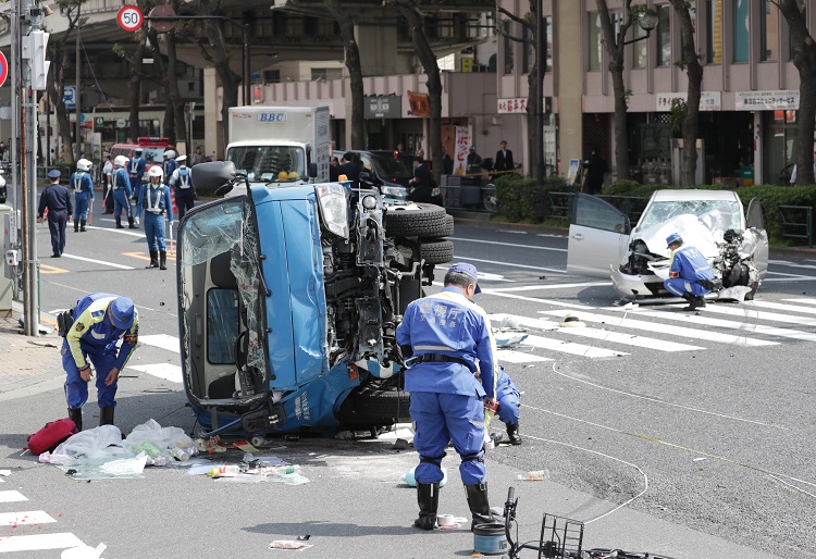 ごみ収集車と乗用車が衝突し、歩行者がはねられた事故現場を調べる警察官（時事通信フォト）