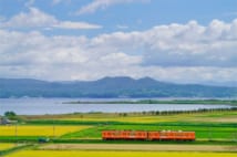 島根県 北松江線の一畑電車。湖畔を望み、田園を走るオレンジ色の小さな電車