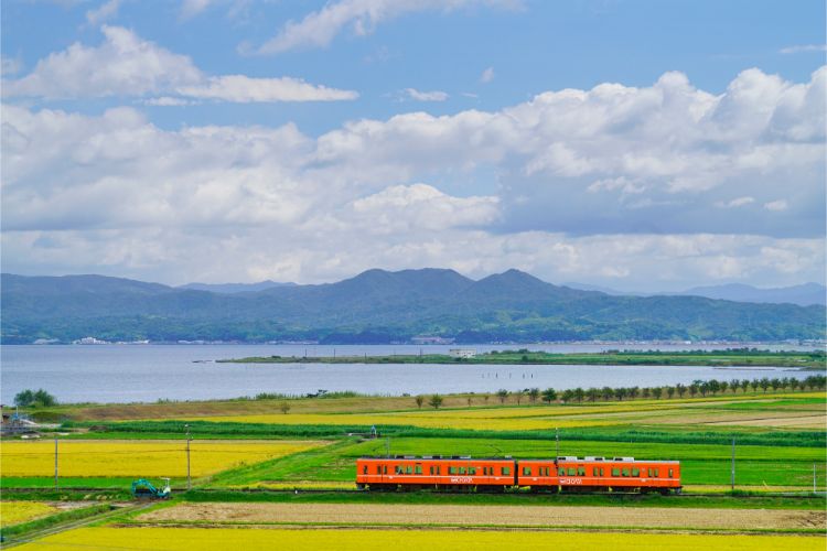島根県　一畑電車　北松江線。湖畔を望み、田園を走るオレンジ色の小さな電車