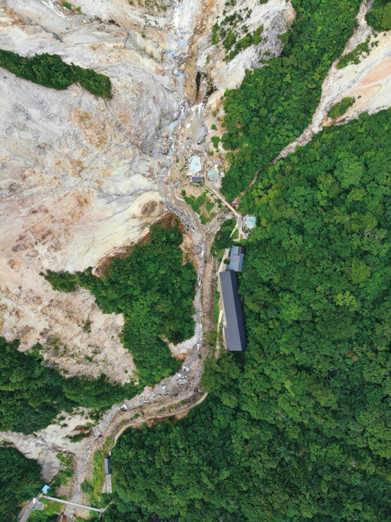背後に原生林、奇岩怪岩がそびえ立つ絶壁に三方を囲まれている桝形屋。上空350mから撮影