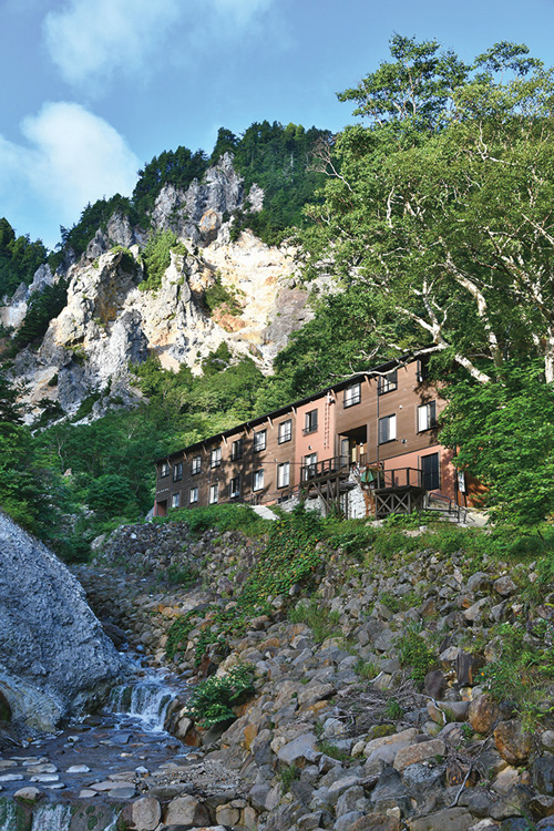 奥深い谷間で山肌にくっつくように建っている。前の川にも温泉水が大量に流れ落ちている