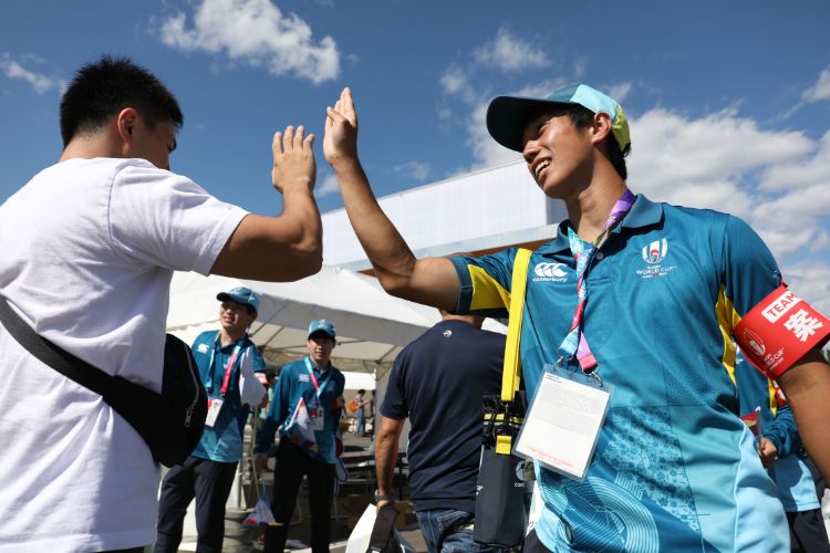 ラグビーW杯2019のボランティアスタッフ（右）。観客と笑顔でハイタッチを交わした（時事通信フォト）