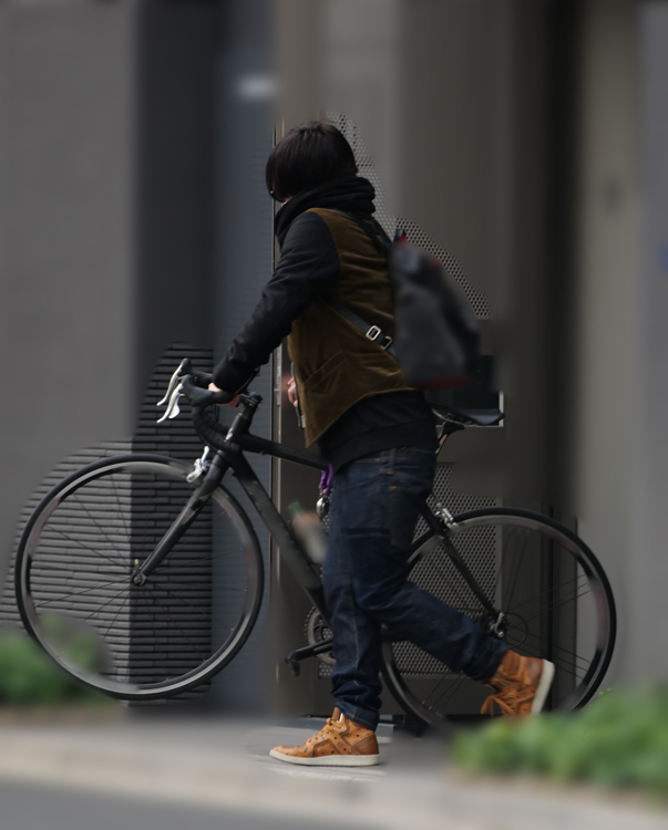 自転車を持ってマンションを出る秋山