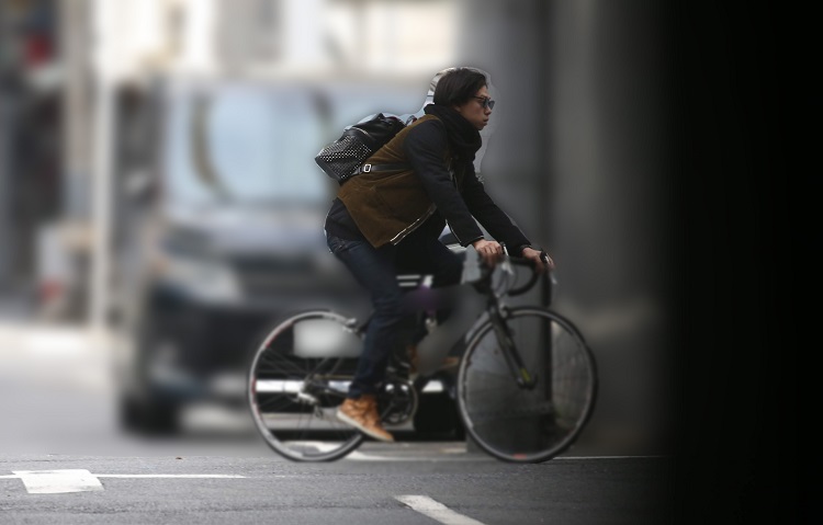 マンションを出て自転車で出かける秋山