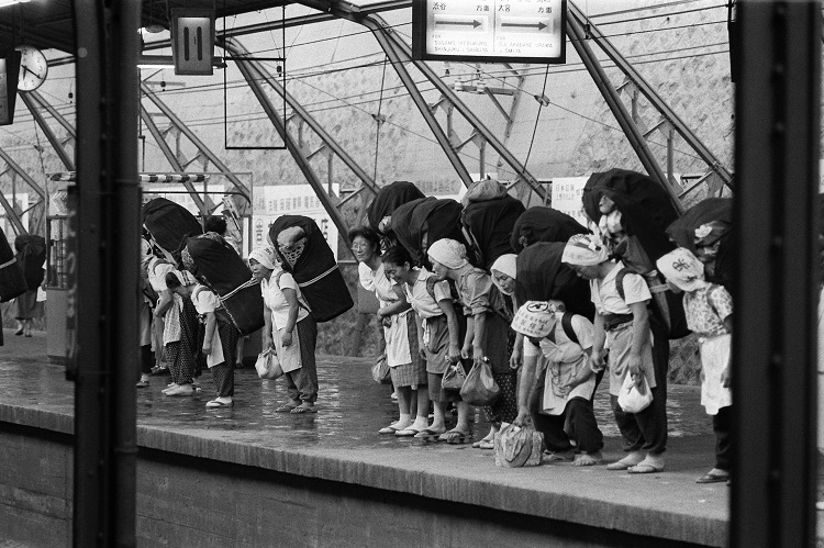 1960年代の東京・日暮里駅。大きな荷物を背負って電車を待つ「かつぎやさん（行商の女性）」たち（時事通信フォト）