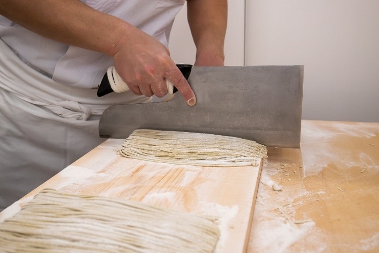 手揉みのそば粉を面状にして麺に揃えていく蕎麦切り。熟練した職人の技術が冴える