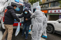 Fully protected medical staff help a patient off the ambulance outside the hospital in Wuhan in central China's Hubei province Sunday, Jan. 26, 2020.