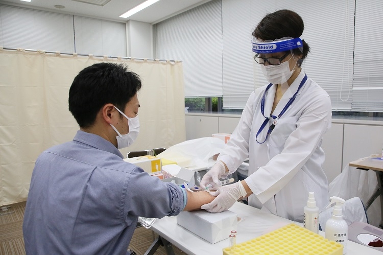 新型コロナウイルス感染歴を調べる抗体検査の採血のデモンストレーション（時事通信フォト）
