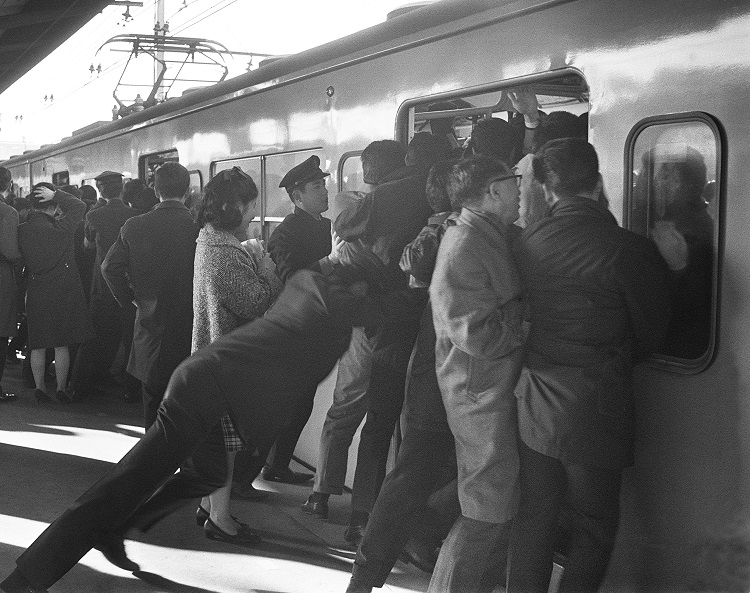 ぎゅう詰めの車内に通勤客を押し込む国鉄職員。1967年新宿駅（時事通信フォト）