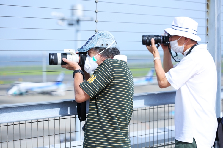 空港で真剣な表情で撮影を行う