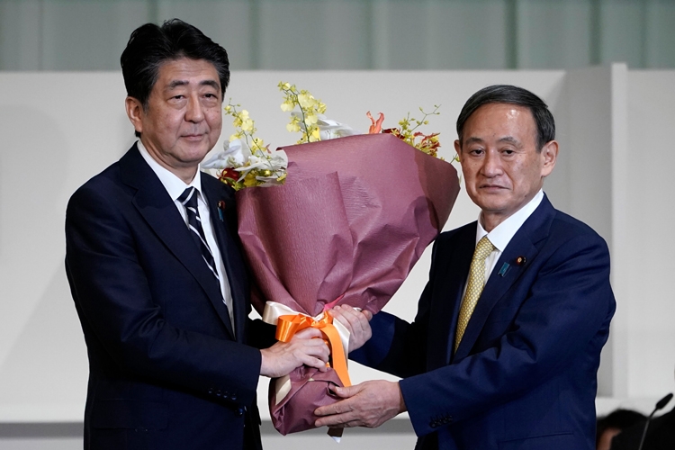 総裁に選出されたその日に、安倍首相に花束を渡す菅氏（時事通信フォト）