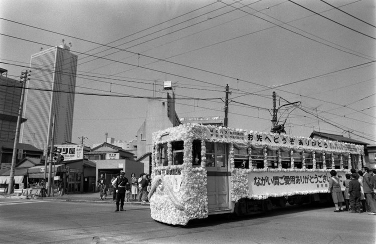 1978年、東京都電のワンマン化を記念して走る花電車。左は日本一の高層ビル「サンシャイン60」（時事通信フォト）