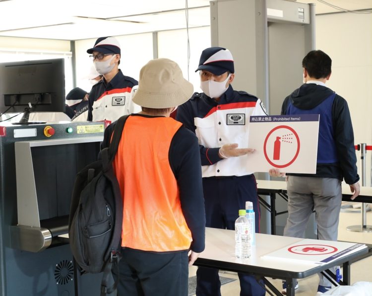 東京五輪・パラリンピックに向けた実証実験の手荷物検査で、持込禁止物品を案内する警備スタッフ（時事通信フォト）