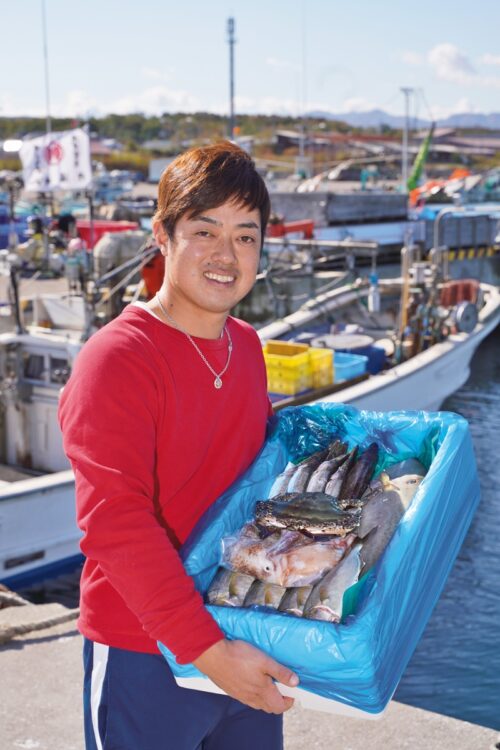 漁師の吉岡奨悟さん。一番人気はその日の漁によって中身が変わる「お楽しみセット」（3024円～、期間限定送料無料）。この日の内容は、ワタリガニ、カワハギ、カンパチ、カマスなどで、魚の種類や処理方法について要望があればできる限り応えるという