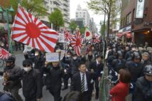 日章旗や旭日旗を振りながら大久保通りを行進するデモ参加者。韓国系の商店や料理店が集まる新宿・新大久保で在日外国人排外などを叫ぶデモが行われた。写真は2013年3月（時事通信フォト）