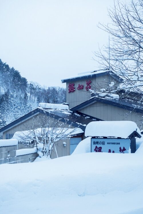 露天風呂の湯けむりの向こうには山や銀山川が見え、水墨画のような見事な雪景色が広がる