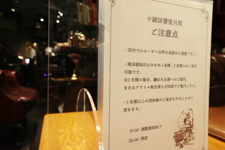 2人以下での来店を求めるバー店内の注意書き（イメージ、時事通信フォト）