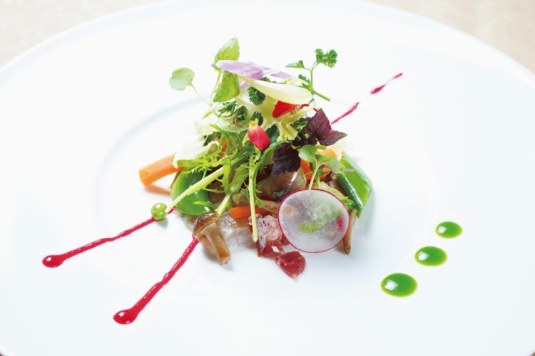 総料理長による就航30周年を記念したフルコースのディナーの1皿(例)。昆布締めしたヒラメの表面を炙った焼霜造りを10種類以上の野菜が彩る