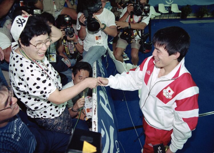 1992年のバルセロナ五輪で獲得した金メダルを愛子さんの胸にかけて握手する古賀氏（時事通信フォト）