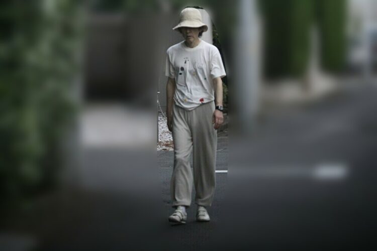 帽子を目深にかぶりTシャツ姿で街を歩く田村さん（2012年撮影）