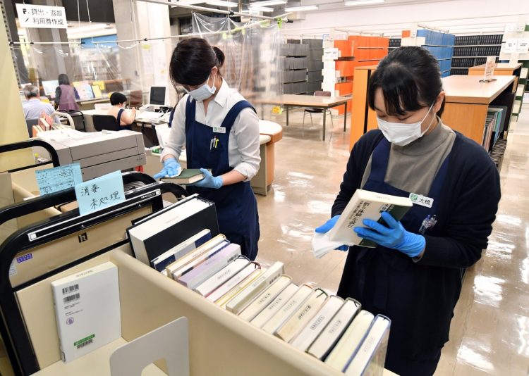 図書館では本を1冊ずつ拭くケースも（写真／共同通信社）