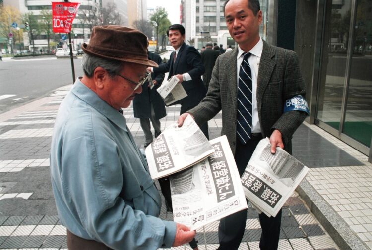 1997年11月17日、北海道拓殖銀行本店前で「拓銀破たん」の号外を受け取る市民（時事通信フォト）
