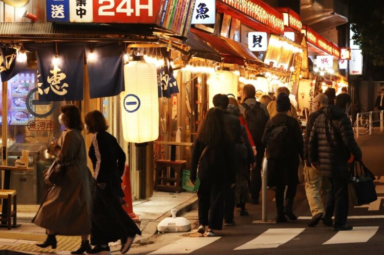 飲食店への営業時間の短縮要請が全面的に解除され、夜を迎えた東京・有楽町の飲食店街を歩く人たち=10月25日午後、東京都千代田区(時事通信フォト)
