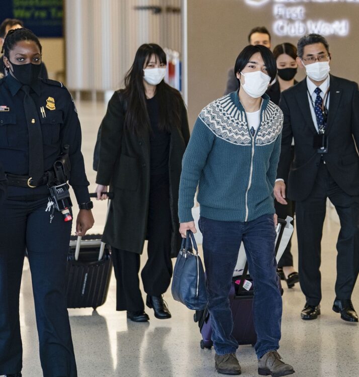 屈強な警察官に囲まれて空港内を移動（写真／共同通信社）