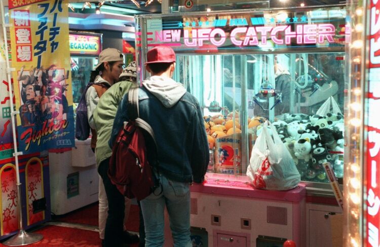 1993年、新宿区歌舞伎町のゲームセンターで夜遅く、クレーンゲームに興じる若者たち（時事通信フォト）