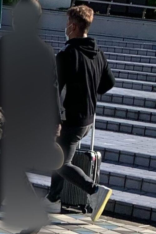 スーツケースを引いて移動する大下。靴はナイキのスニーカー