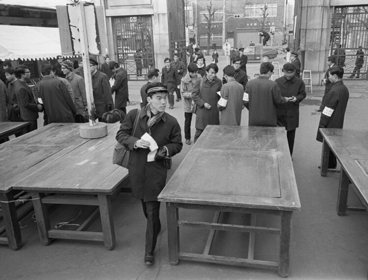 1970年3月、東京大学入学試験。検問所で受験票を見せ、机で固めた狭い通路を通って試験場に向かう受験生たち（時事通信フォト）